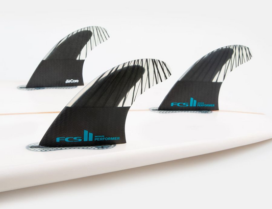 FCS II PCC Performance Core Carbon Medium Tri Fin Set showing 3 fins in surfboard