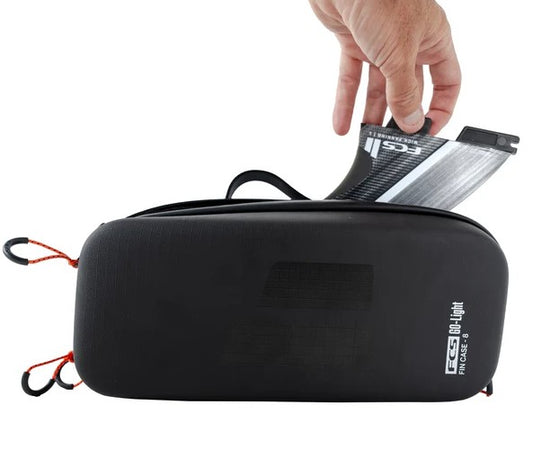 FCS Go-Lite Surfboard Fin Case - 8 sets in black showing a fin being put in