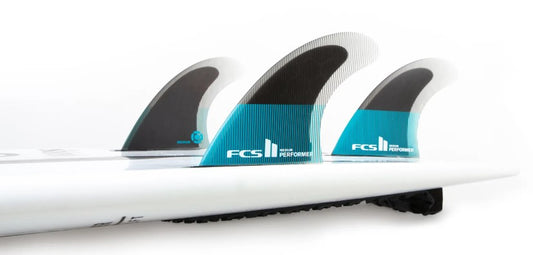 FCS II Performer PC Medium Tri Surfboard Fin Set in a white surfboard in black, blue and clear colourway