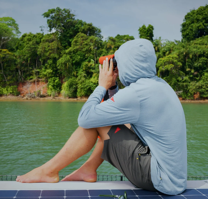 Florence Marine X Airtex Long Sleeve Hooded Shirt in heather light sea blue on man sitting by the river