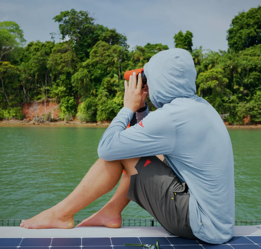 Florence Marine X Airtex Long Sleeve Hooded Shirt in heather light sea blue on man sitting by the river