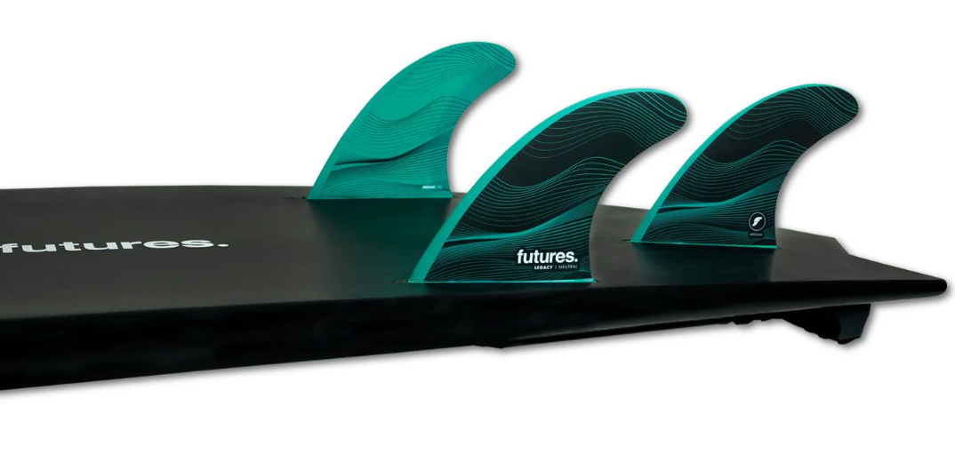 Futures Legacy HC Thruster Fin Set in black and green in tail of a black surfboard