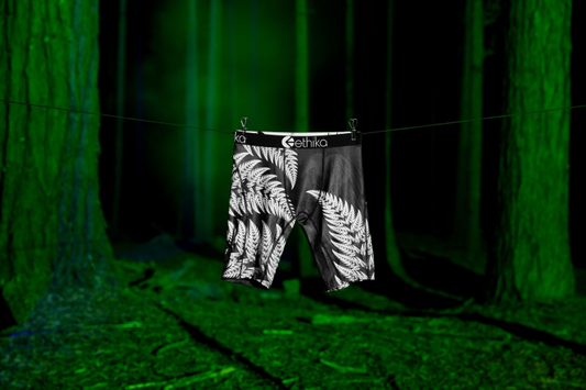 Ethika Mens Silver Legacy Staple Boxers with silver fern design from front hanging in a forest