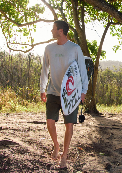 O'Neill TRVLR Cargo 20" Hybrid Shorts
 in army colourway on surfer carrying his surfboard