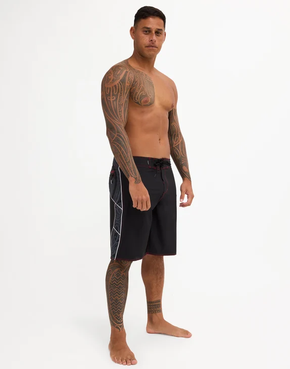 Quiksilver Tai Kehu Takarangi 21" Maori Boardshorts in black, white and red on Kehu Butler from the front on side angle
