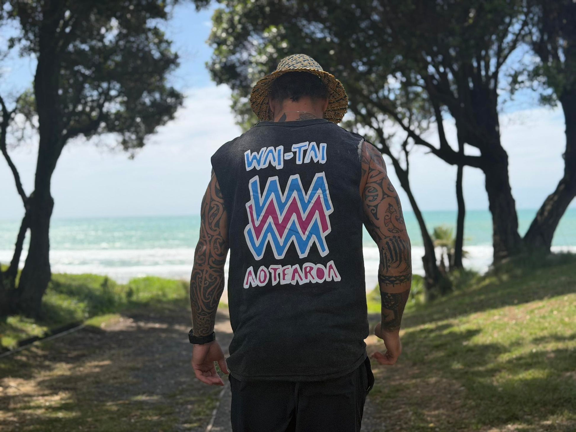 Wai-Tai Mura Stonewash Heavyweight Unisex Muscle in black stonewash with flouro logo on Maia Gibbs at Stockroute surf spot Gisborne