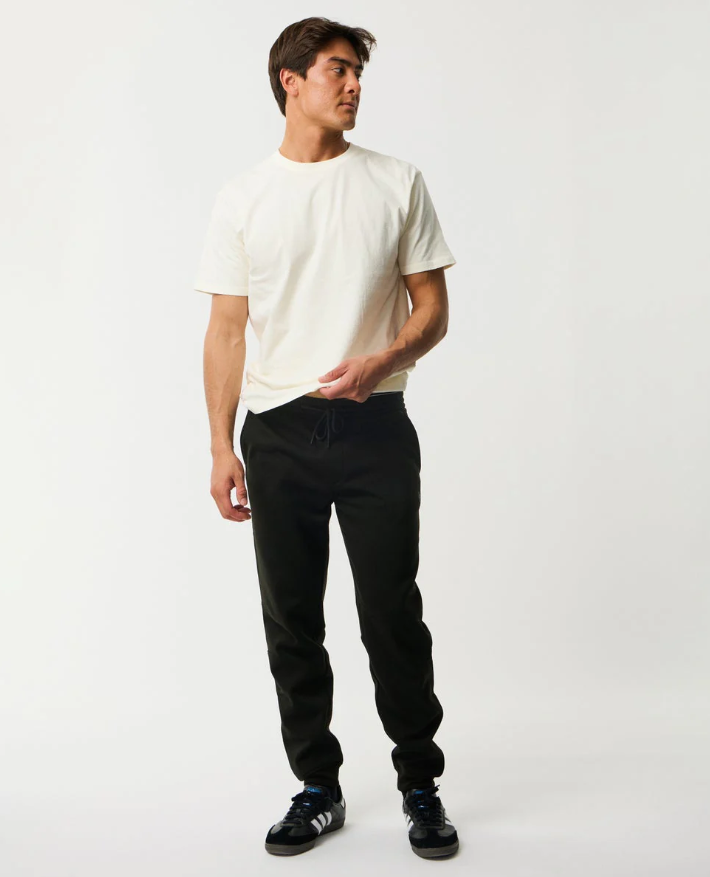 Rip Curl Anti Series Departed DWR Bonded Fleece Trackpant in black on model in white tee