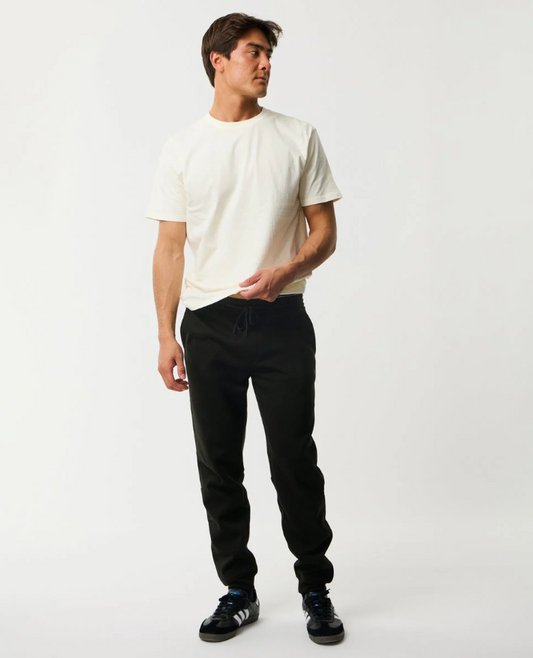Rip Curl Anti Series Departed DWR Bonded Fleece Trackpant in black on model in white tee