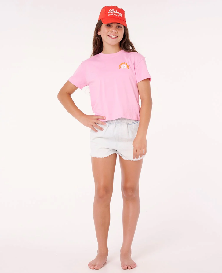 Rip Curl Girl's Surf Puff Baby Crop Tee in pink on girl model in denim shorts and red cap from front