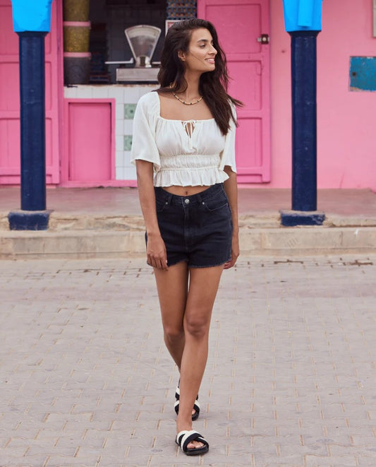 Roxy Eva Denim Shorts in black on model in white fashion top in a pink painted town