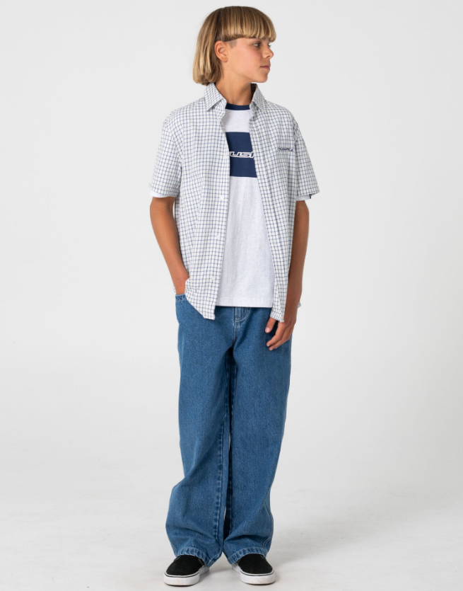 Rusty Defender Boys Short Sleeve Shirt in cream check on model in blue jeans from the front with shirt open