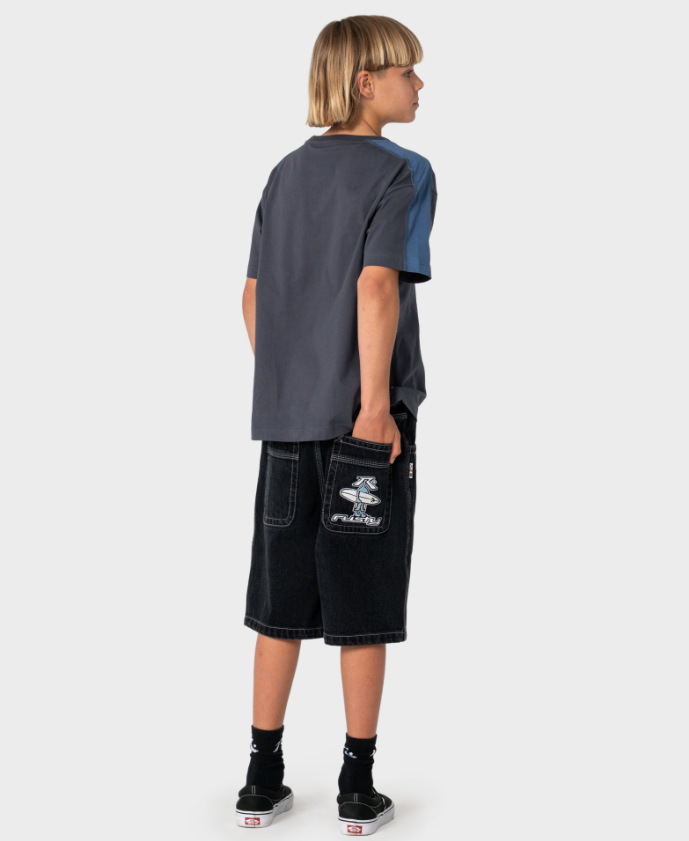 Rusty Dr Dot Baggy Boys Denim Shorts in blackout colour on boy in Rusty t-shirt from the rear showing embroidered image on pocket