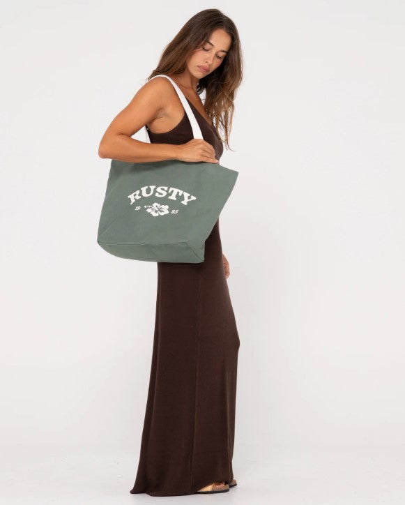 Rusty Essential Tote Bag in sage colour being held by a model wearing a brown dress