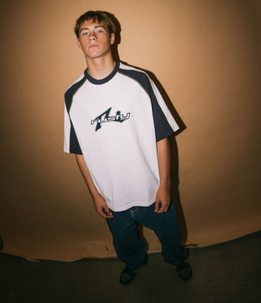 Rusty Fade-R Short Sleeve Tee in white with navy detail on model from front with brown backgrounds