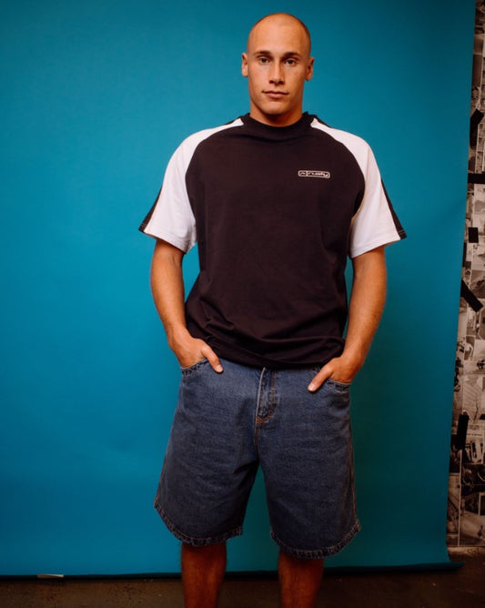 Rusty Flip Daddy Low Ballin 23" Denim Shorts in middy blue on model in black and white t-shirt from front