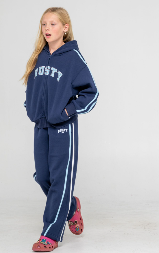 Rusty Girls Team Varsity Wide Leg Jogger Pants in navy with blue and white stripes on blonde model wearing rusty hoodie
