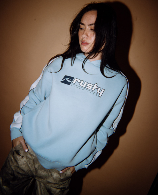 Rusty Hailstone Oversized Hooded Fleece in retro blue on model from front with brown background