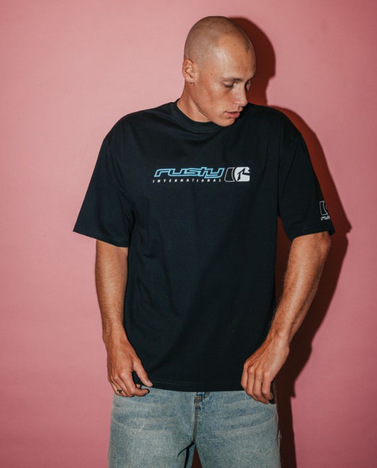 Rusty Jetsetter Men's T-Shirt  in black on model in denim shorts with red background