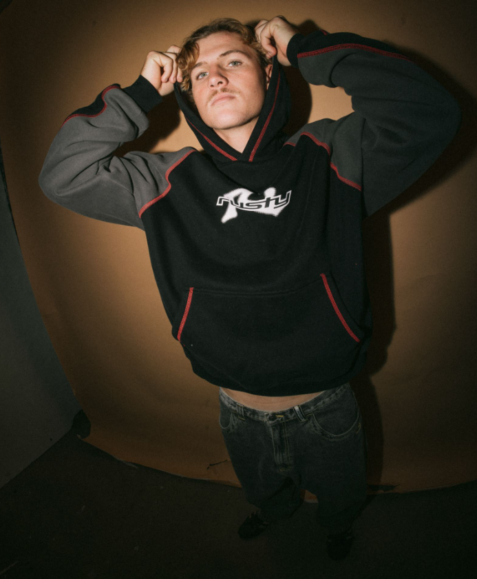 Rusty Paneka Hooded Fleece in bklack with carbon coloured arms and red stitching on model from front pulling up his hood