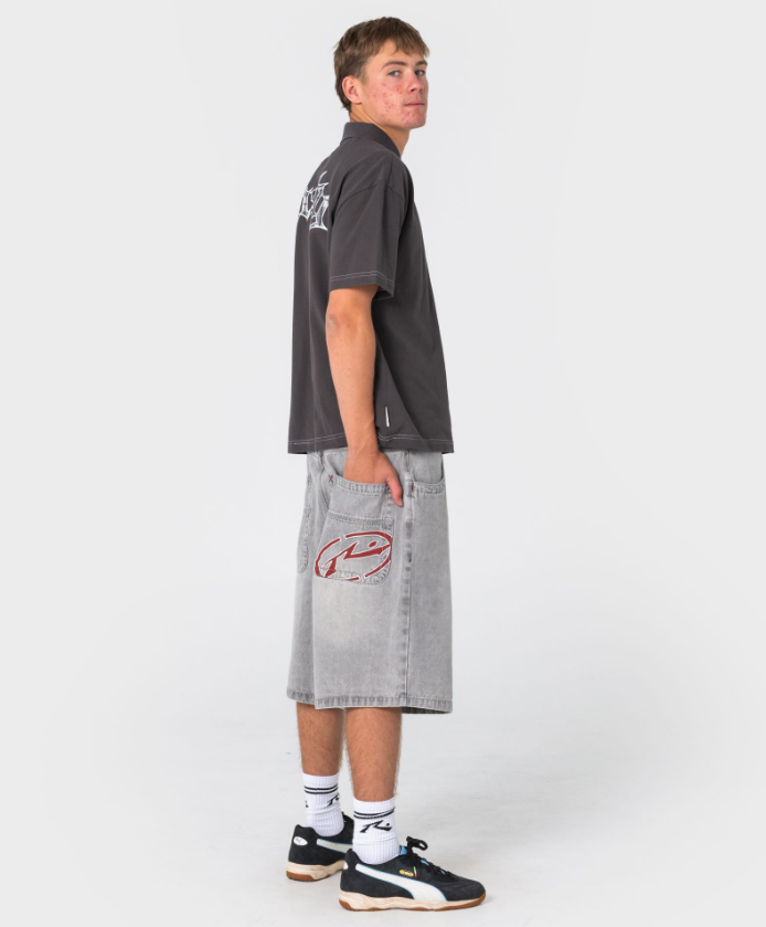 Rusty Turbo 2.0 Baggy 24" Denim Shorts in storm grey colourway on model in Rusty polo from the back showiong large Rusty pocket rear embroidery