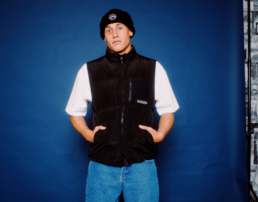 Rusty United Thinsulate Men's Beanie in black on model in black rusty puffer vest from front and blue background
