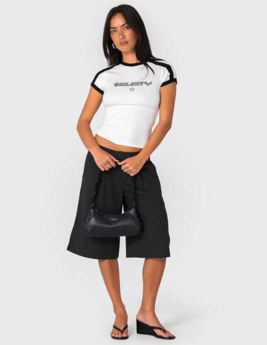 Rusty Wild Saint Shoulder Bag in black held by a model in rusty tee