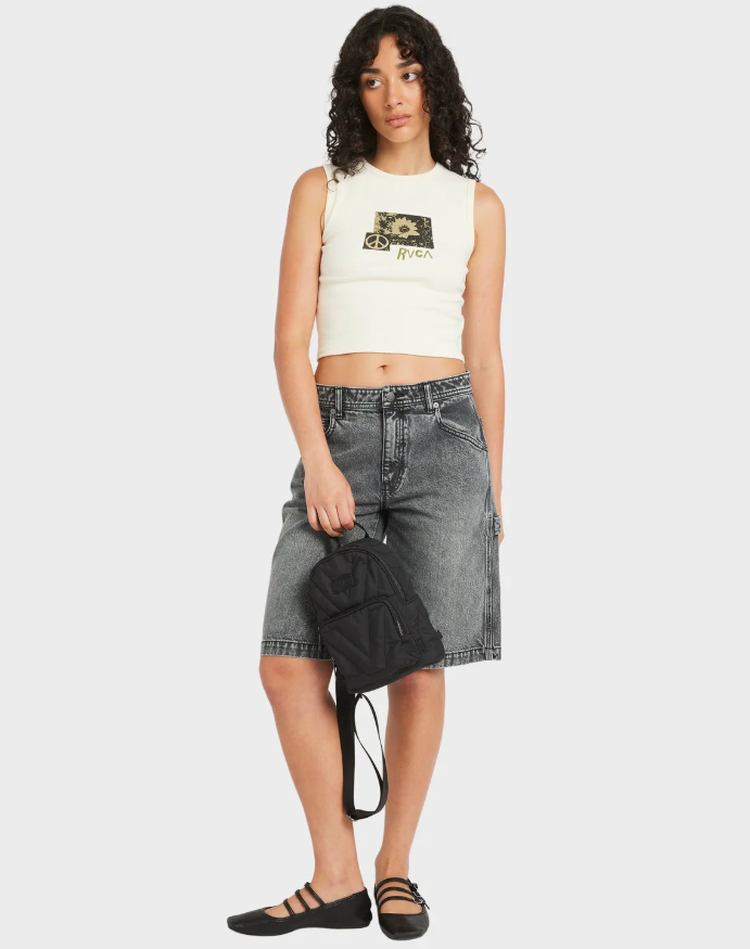 Woman wearing a white sleeveless top and denim shorts, holding a black bag on a white background