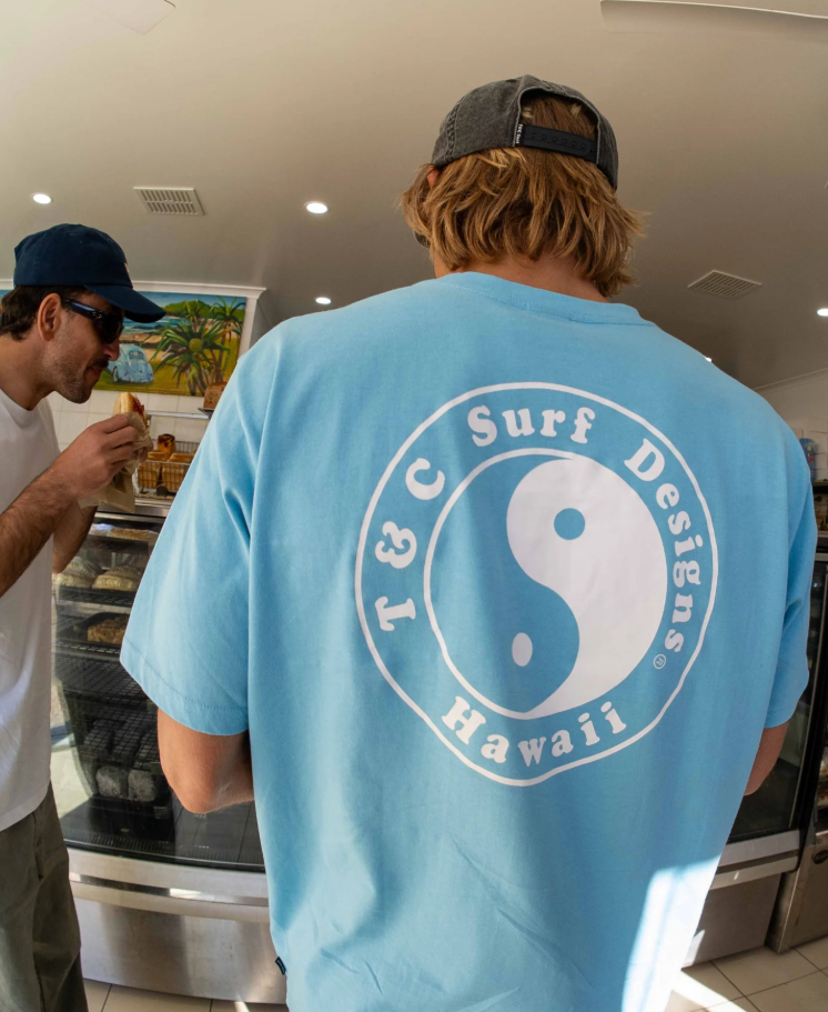 T & C OG Logo Men's T-Shirt in light blue from rear on man at bakery