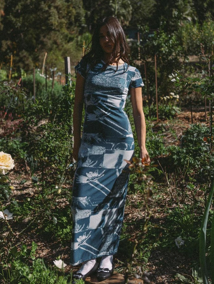 Dark haired model in a garden wearing the Thrills Alchemy Mesh Midi Dress in new teal colour