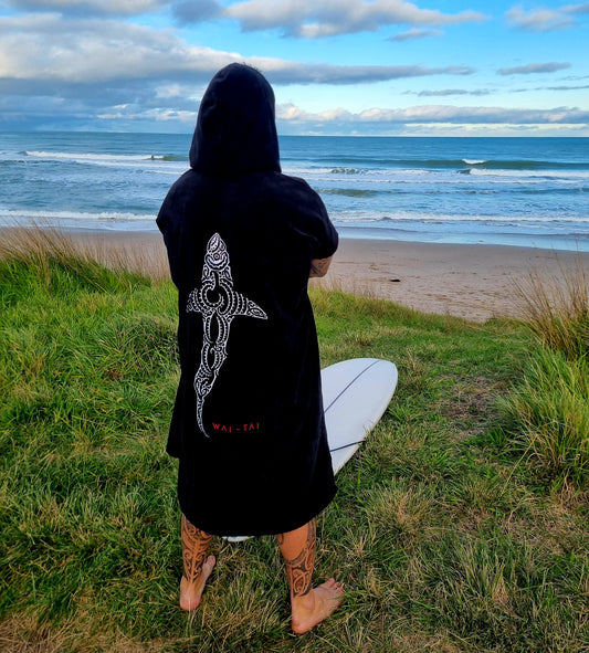 Wai-Tai Kaitiaki Premium Hooded Towel in black on Maia Gibbs at Okitu beach in Gisborne with hood up