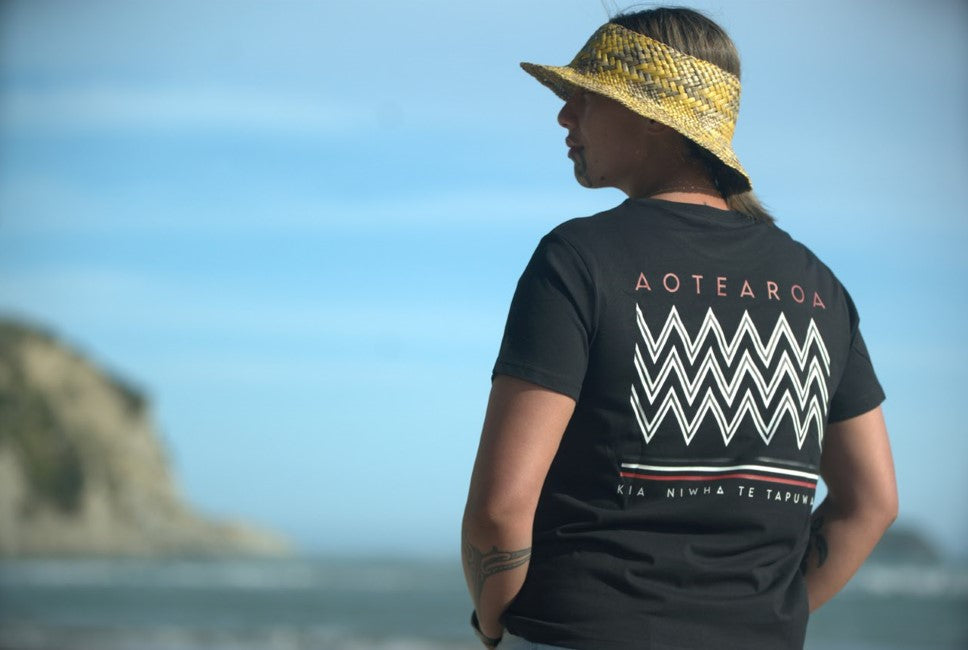 Wai-Tai Womens Tohu Tee in black on model at Kaiti Beach