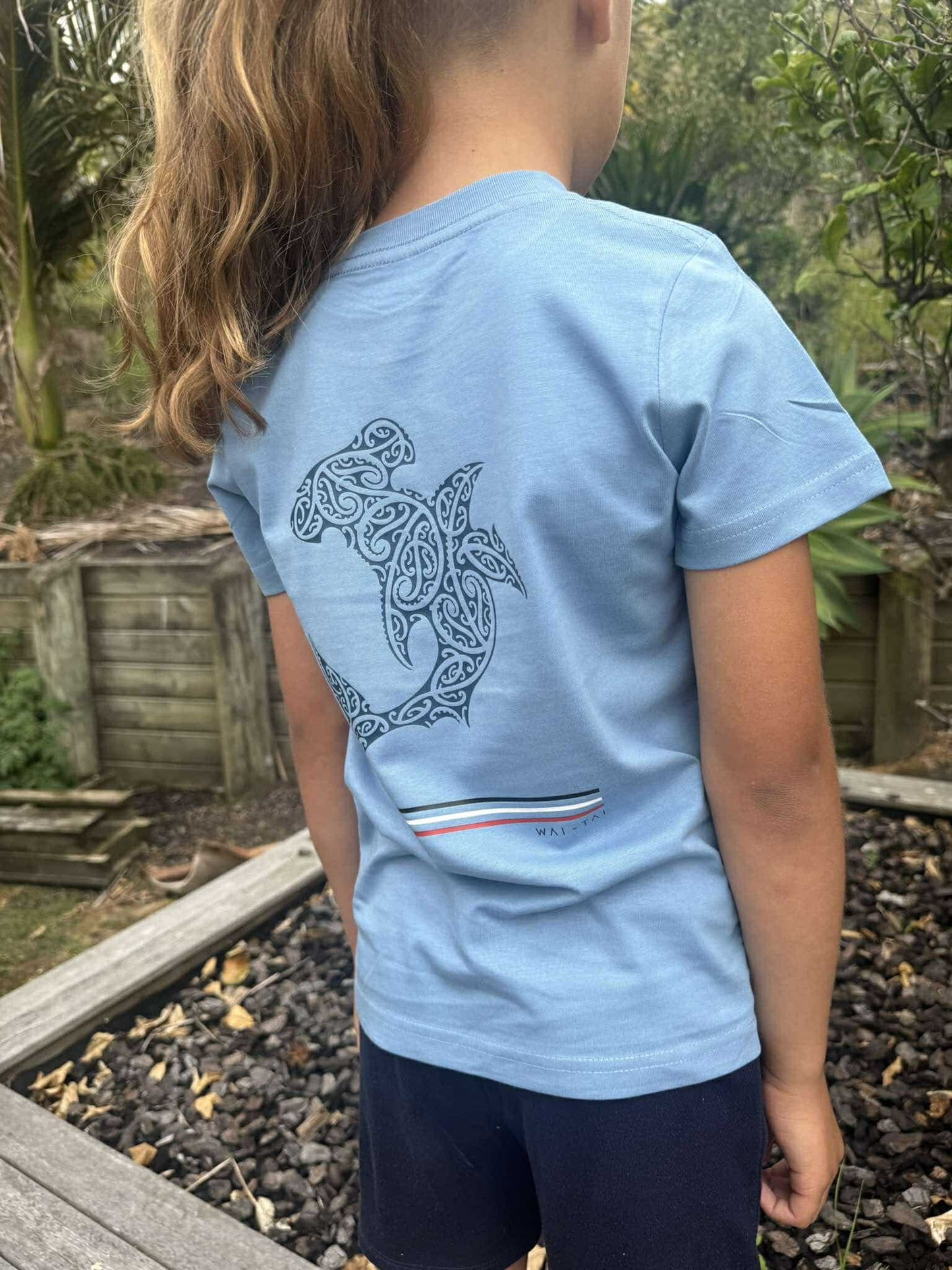 Wai-Tai Kids Mangopare Tee in carolina blue from rear showing hammerhead shark print in navy