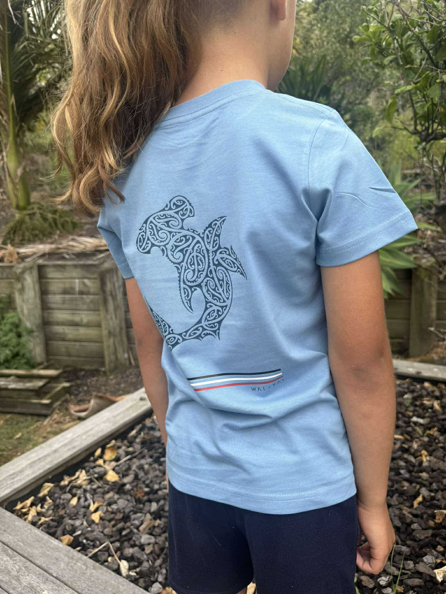 Wai-Tai Kids Mangopare Tee in carolina blue from rear showing hammerhead shark print in navy