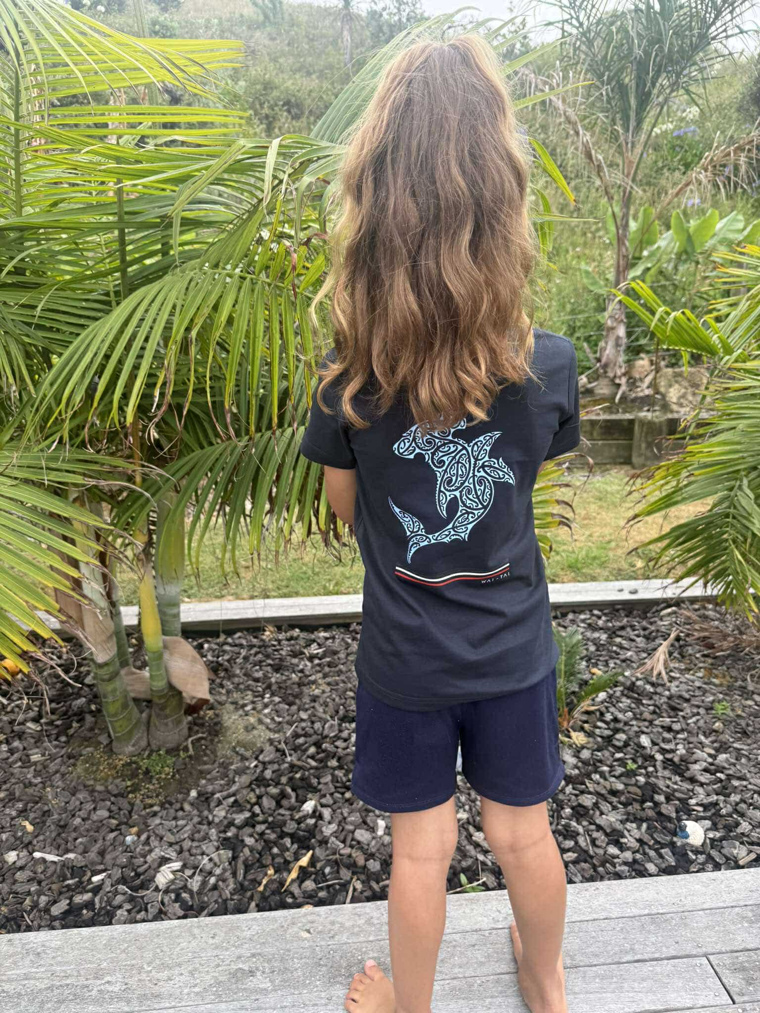 Wai-Tai Kids Mangopare Tee in navy from rear with sky blue hammerhead shark print